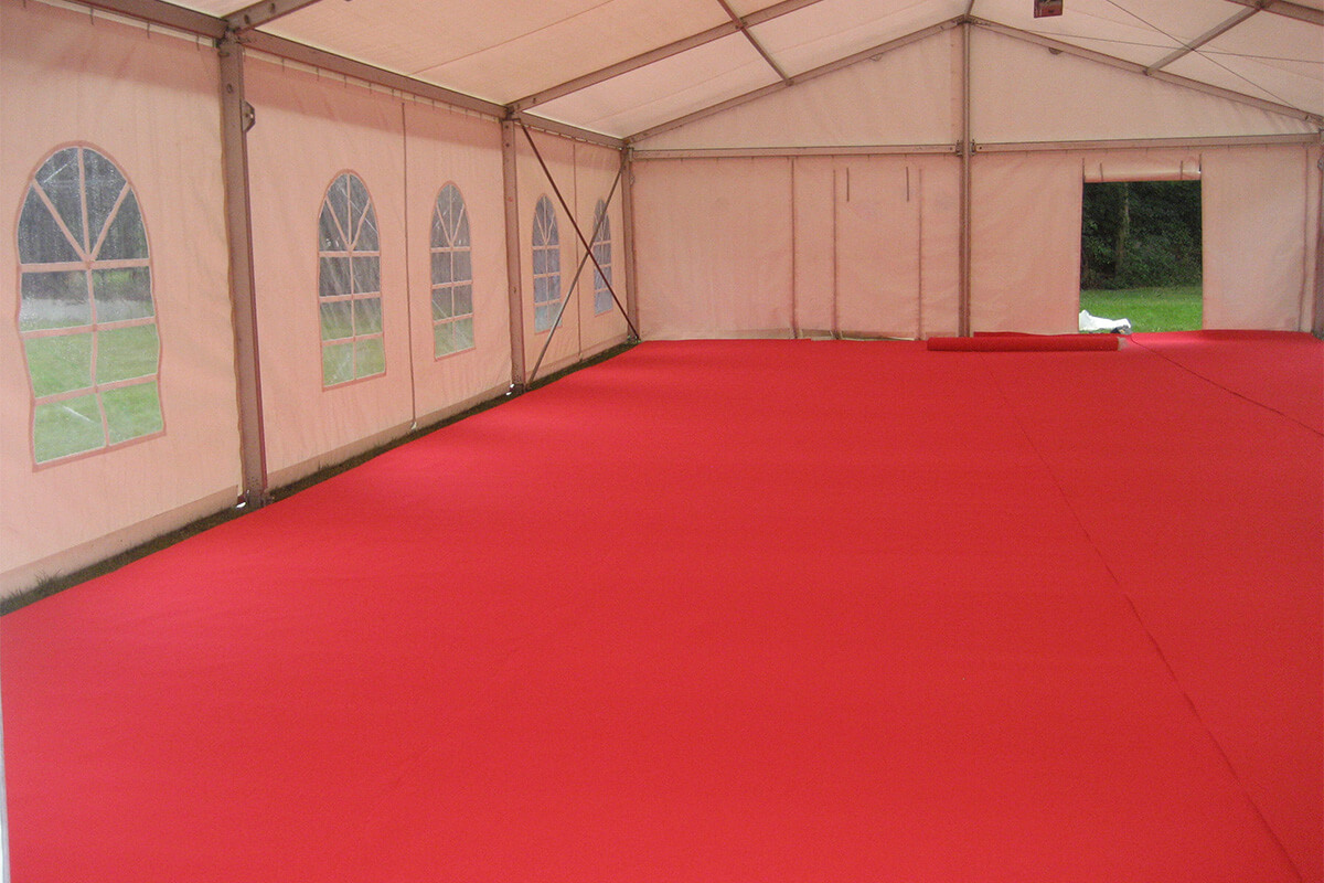 Vue extérieure d’une tente blanche installée dans un jardin, avec un chemin pavé menant à l’entrée.